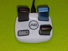 Das weiße, quadratische Ladegerät hat vier Steckplätze für die Akkus. Drei davon sind mit verschiendenfarbigen Akkus besetzt.