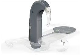 SONNET Prozessor, bei der die Sendespule bereits in geöffneten durchsichtigen Kunststoffhülle liegt. Der andere Teil der Hülle ist noch geöffnet